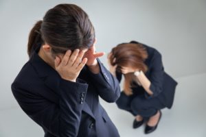 頭を抱えるスーツの女性